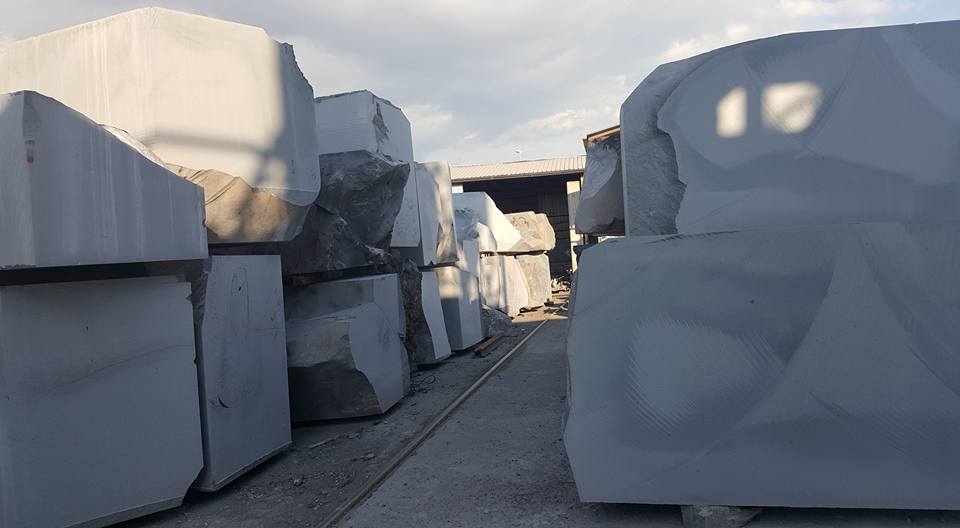 Grandi blocchi di pietra grigia accatastati in fila, sotto un cielo nuvoloso.