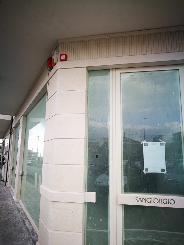 Esterno di un negozio con porta e vetrina in vetro. Un allarme antincendio è installato sulla facciata dell'edificio.