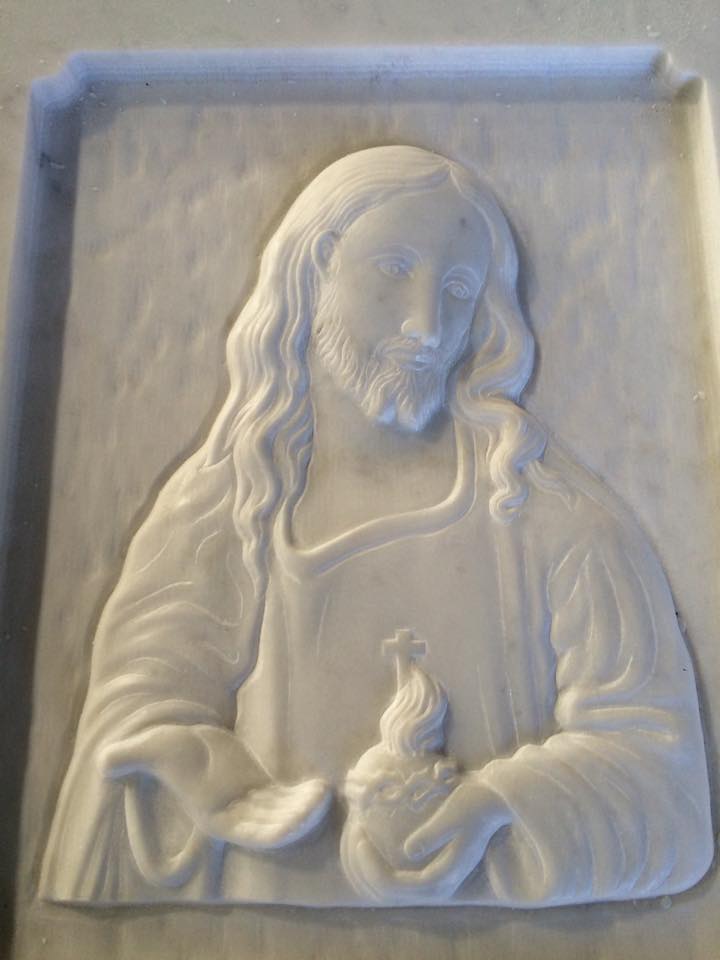 Rilievo bianco raffigurante Gesù Cristo che regge un cuore fiammeggiante.