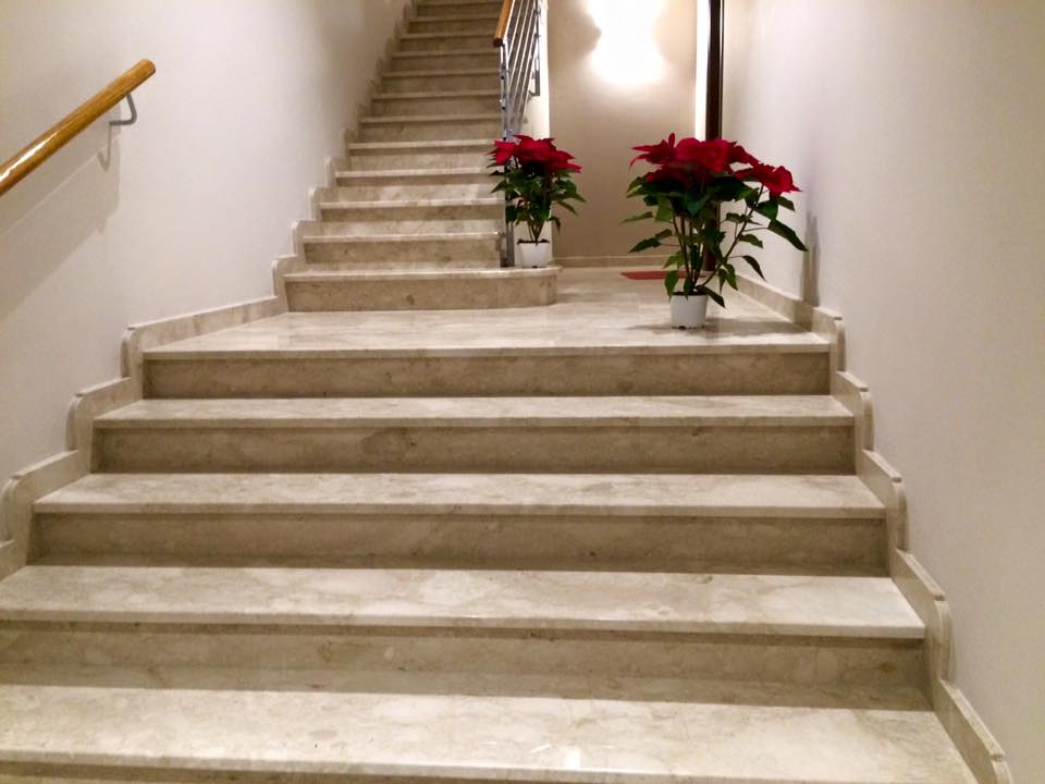 Scala in marmo con due piante di stelle di Natale rosse.