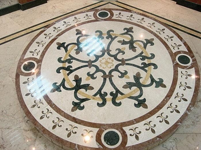 Pavimento circolare in marmo con motivo floreale decorativo nelle tonalità del marrone, verde, crema e nero.