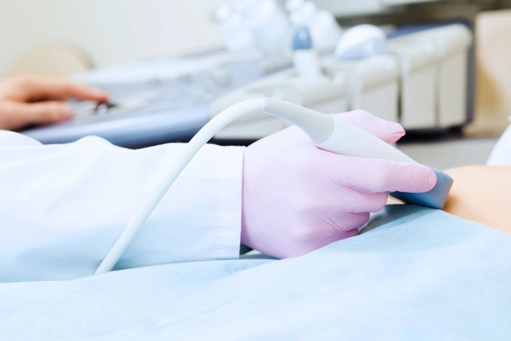 Mano enguantada utilizando una sonda de ultrasonido en un paciente durante un examen médico.