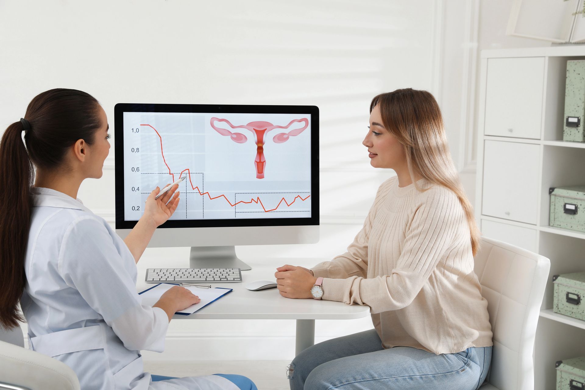 Un médico le muestra a una paciente una gráfica de fertilidad en una computadora en un consultorio clínico bien iluminado.