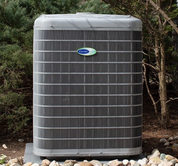 Gray Carrier air conditioner unit in a yard.