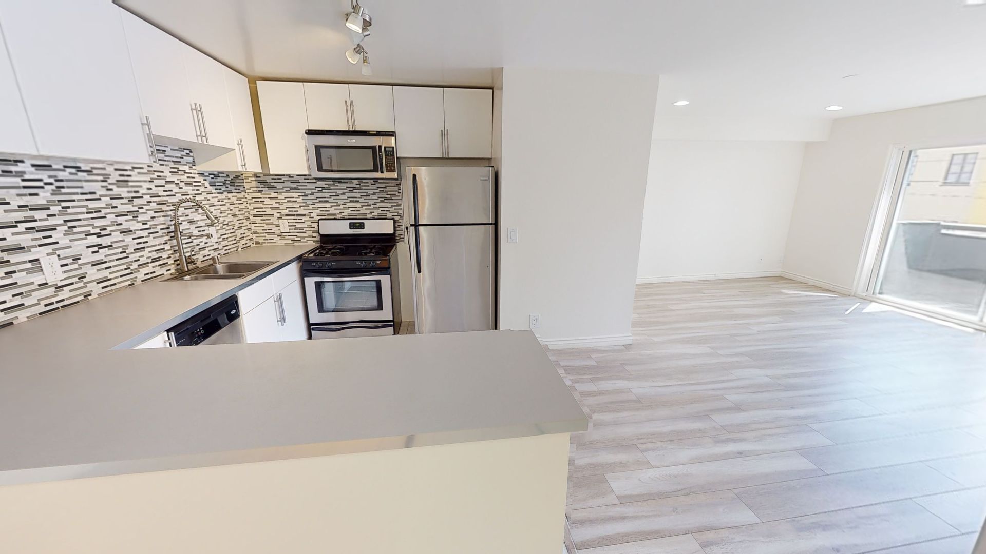 Modern kitchen with white cabinets, stainless steel appliances, and a gray countertop.