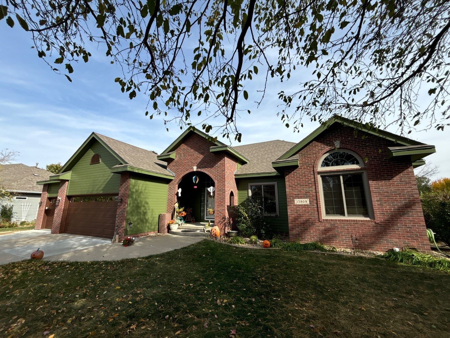 A brick house with a green roof and a tree in front of it.