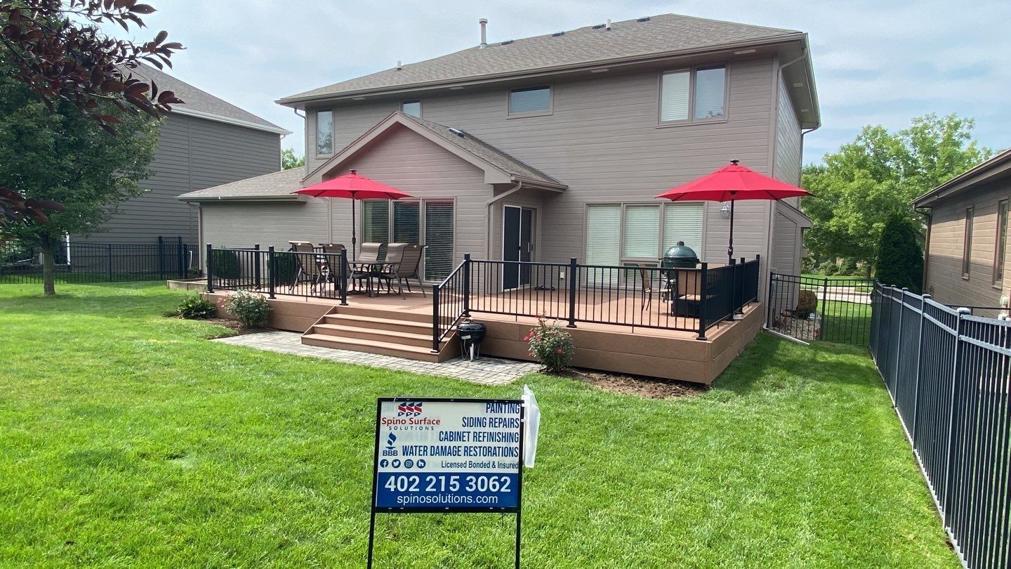 A house with a large deck and a for sale sign in front of it.