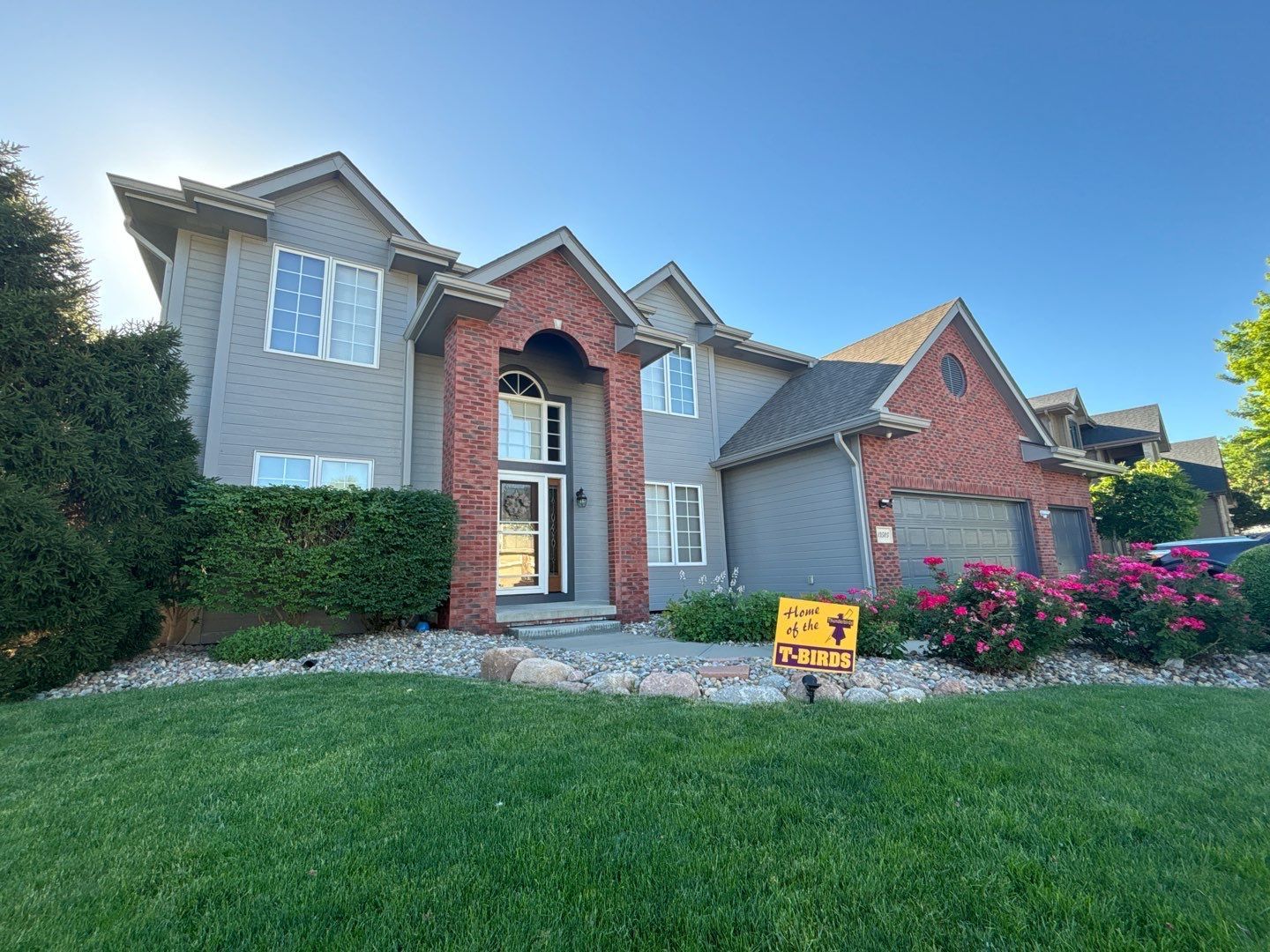 A large house with a for sale sign in front of it.