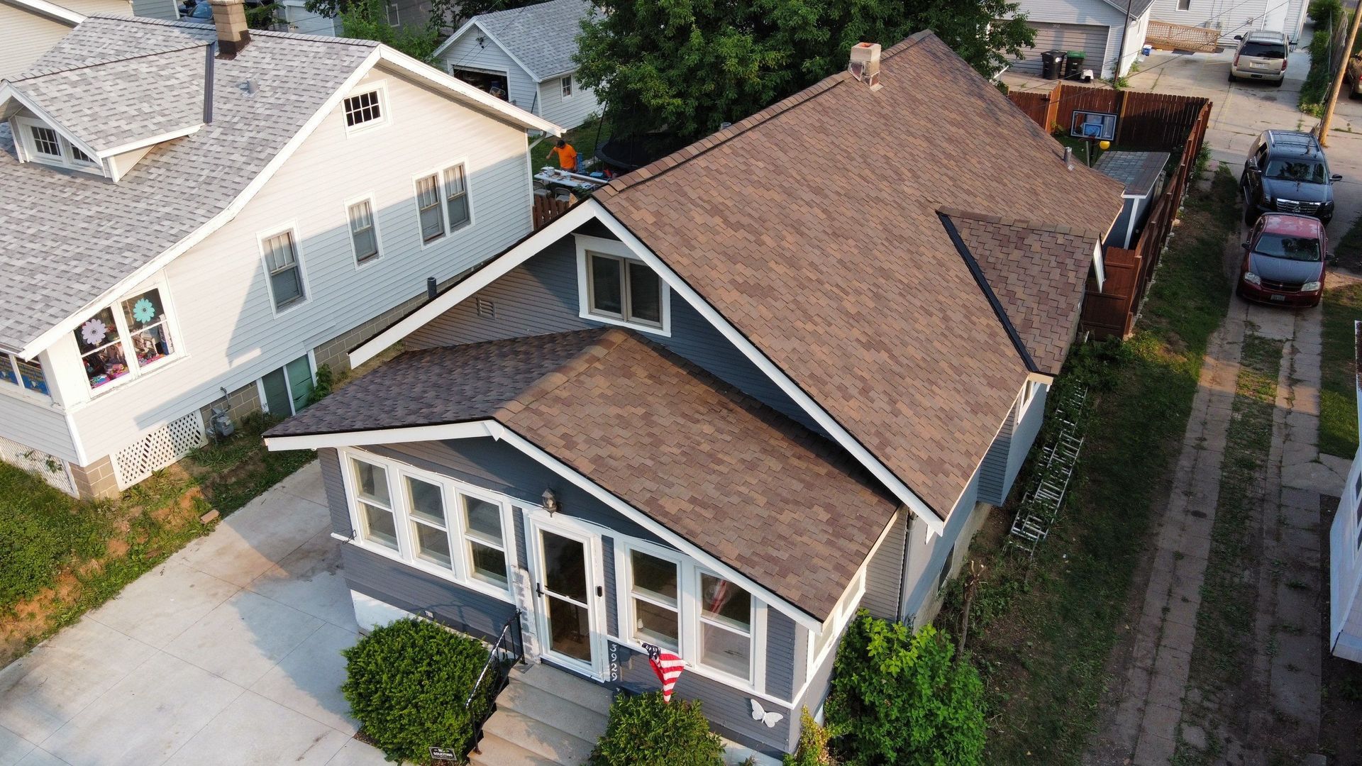 An aerial view of a house with a brown roof in a residential area.