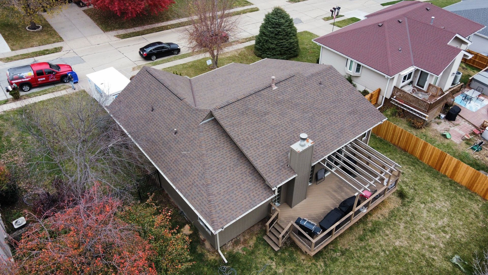 An aerial view of a house with a deck and a red truck parked in front of it.