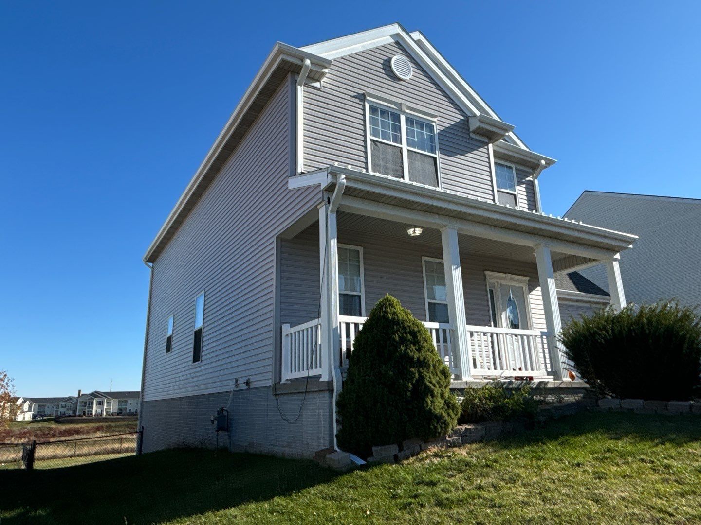 A house with a porch and a blue sky in the background.