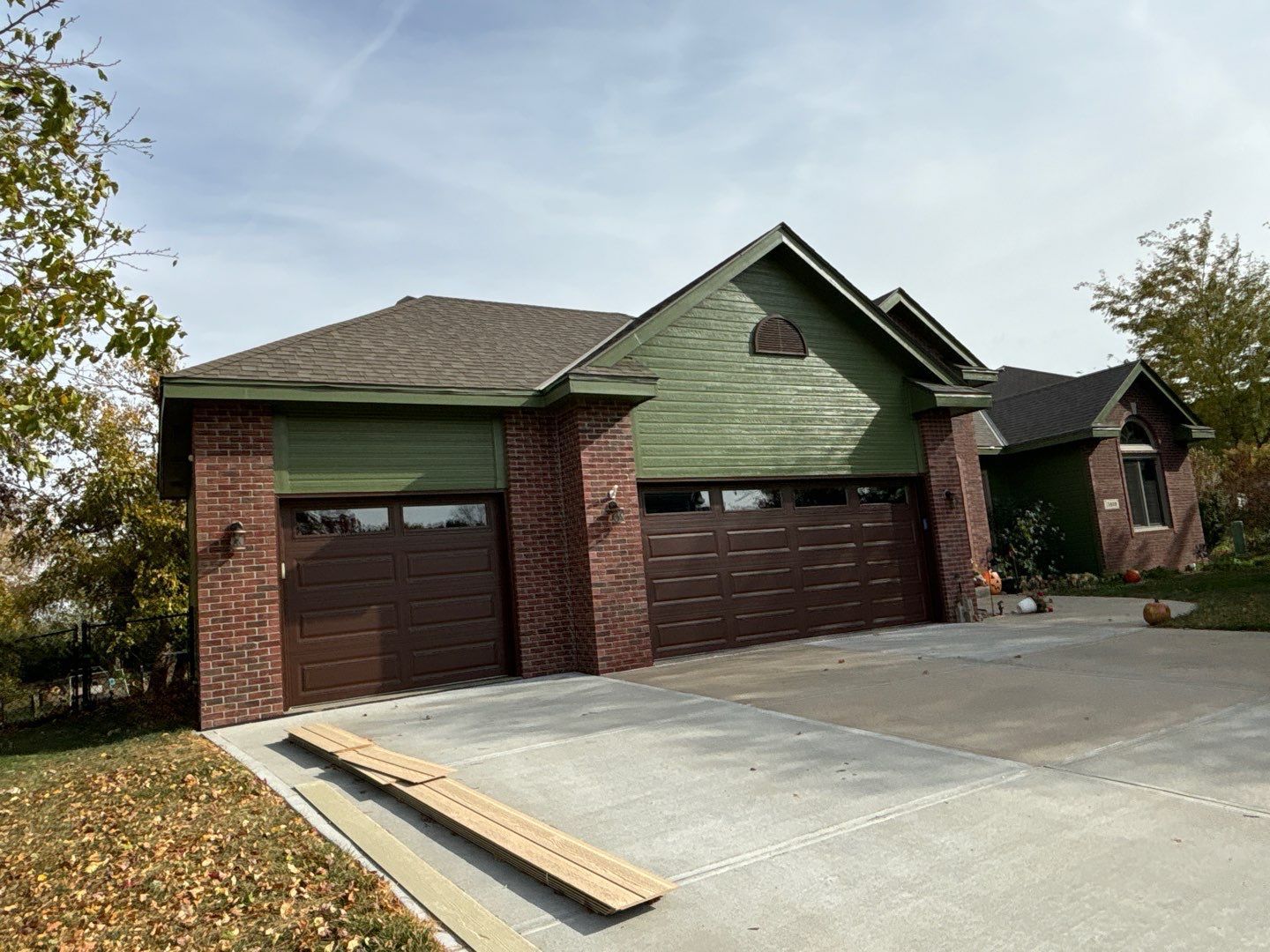 A brick house with a green roof and brown garage doors.