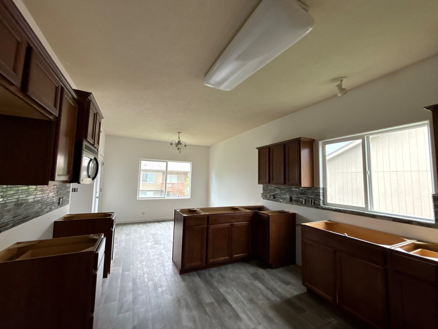 An empty kitchen with wooden cabinets and a large window.