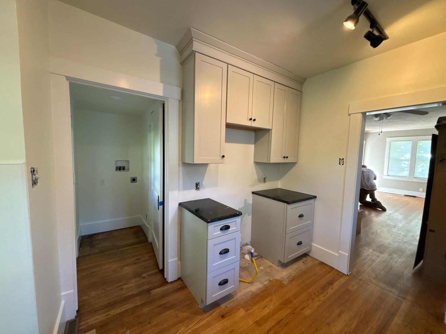 A kitchen with white cabinets and wooden floors is being remodeled.