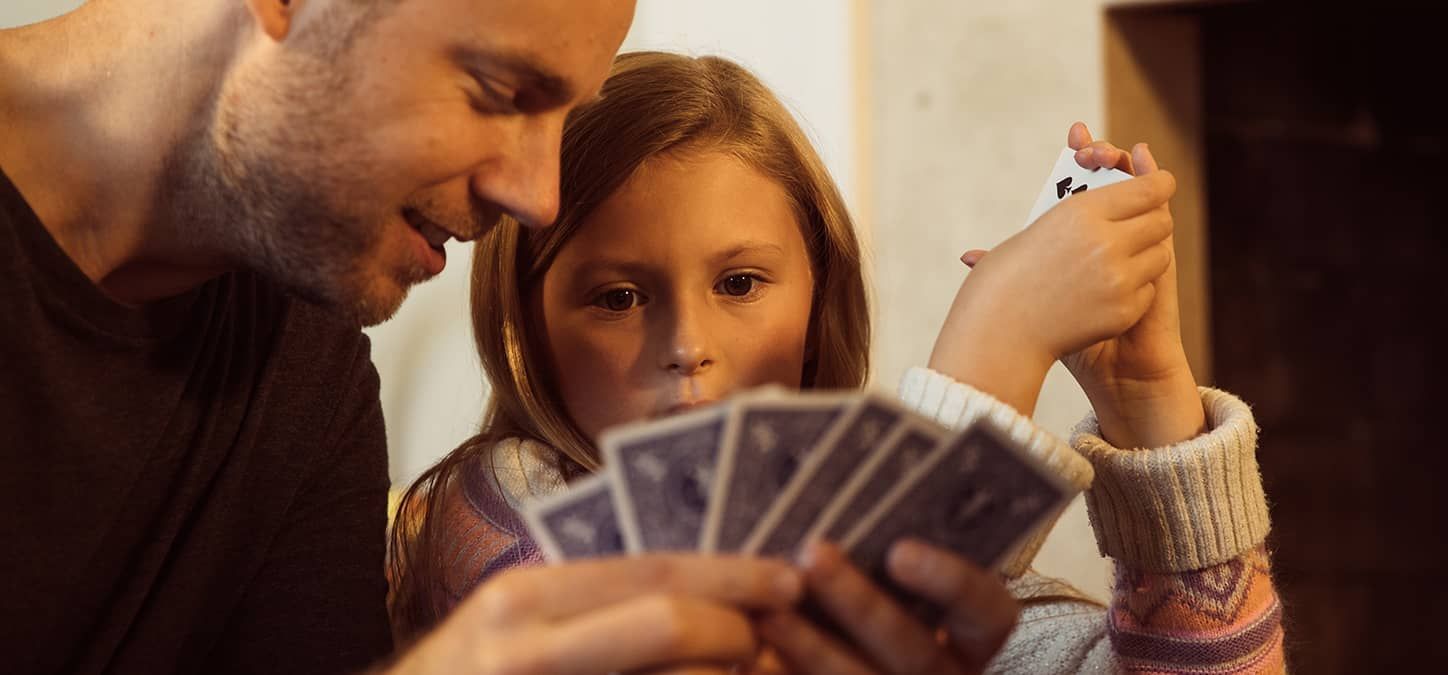 A man and a little girl are playing a game of cards on game night for fun card games