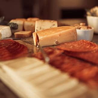 Charcuterie board with cheeses, meats, and nuts. Wooden board, close-up shot.