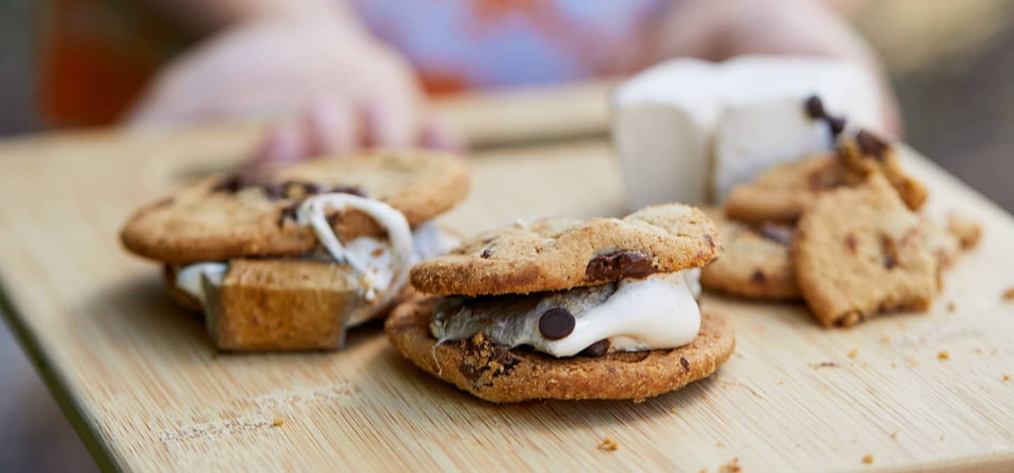 chocolate chip cookie s'mores on a wooden cutting board