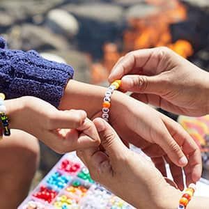 A person is putting a bracelet on a child 's wrist.