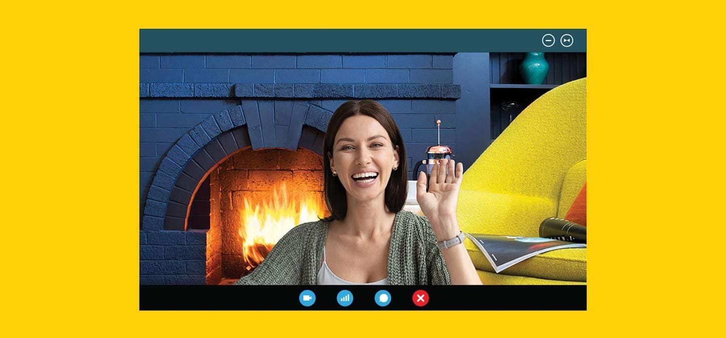 A woman is sitting in front of a fireplace on a video call with a duraflame fire in the background