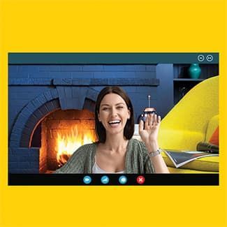 A woman is sitting in front of a fireplace on a video call.