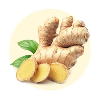 Fresh ginger root with sliced pieces and green leaves against a light background.