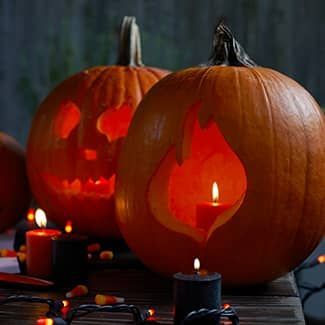Three pumpkins with candles carved into them are sitting on a wooden table.