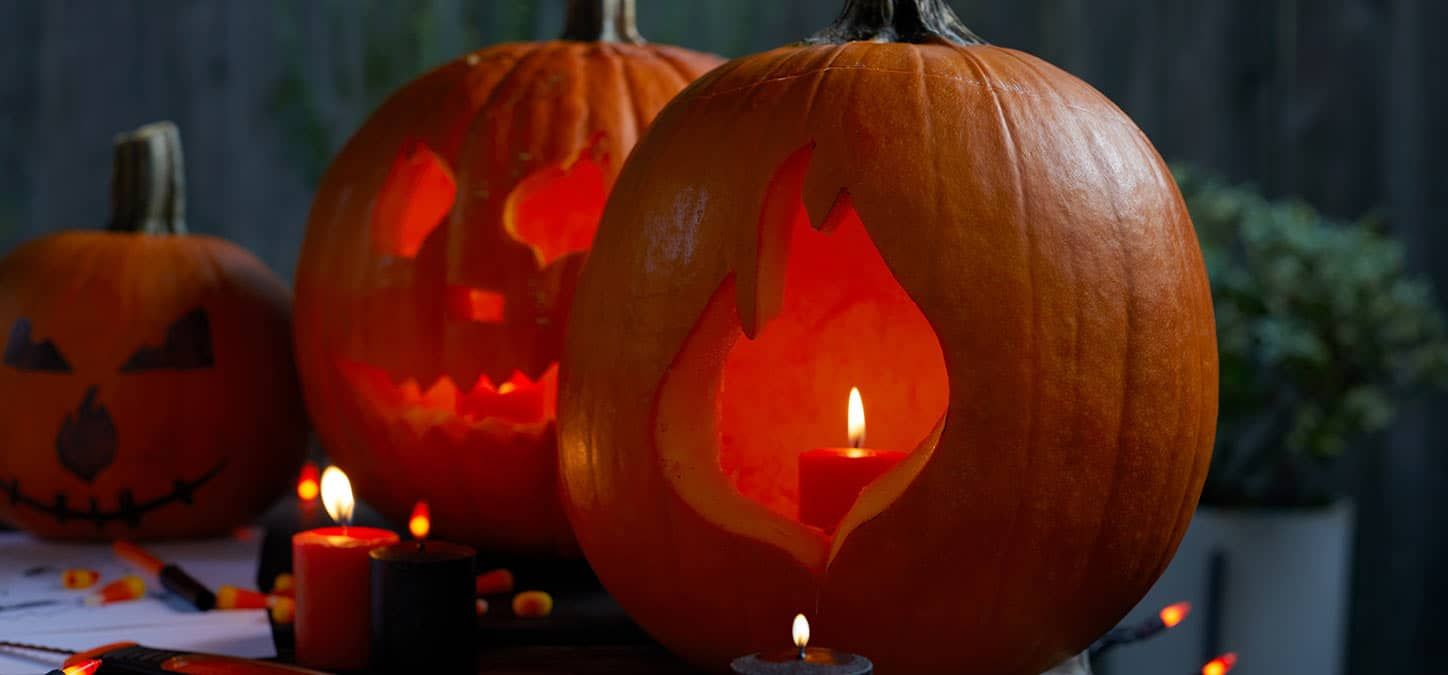 Three carved pumpkins with candles in them are sitting on a table.