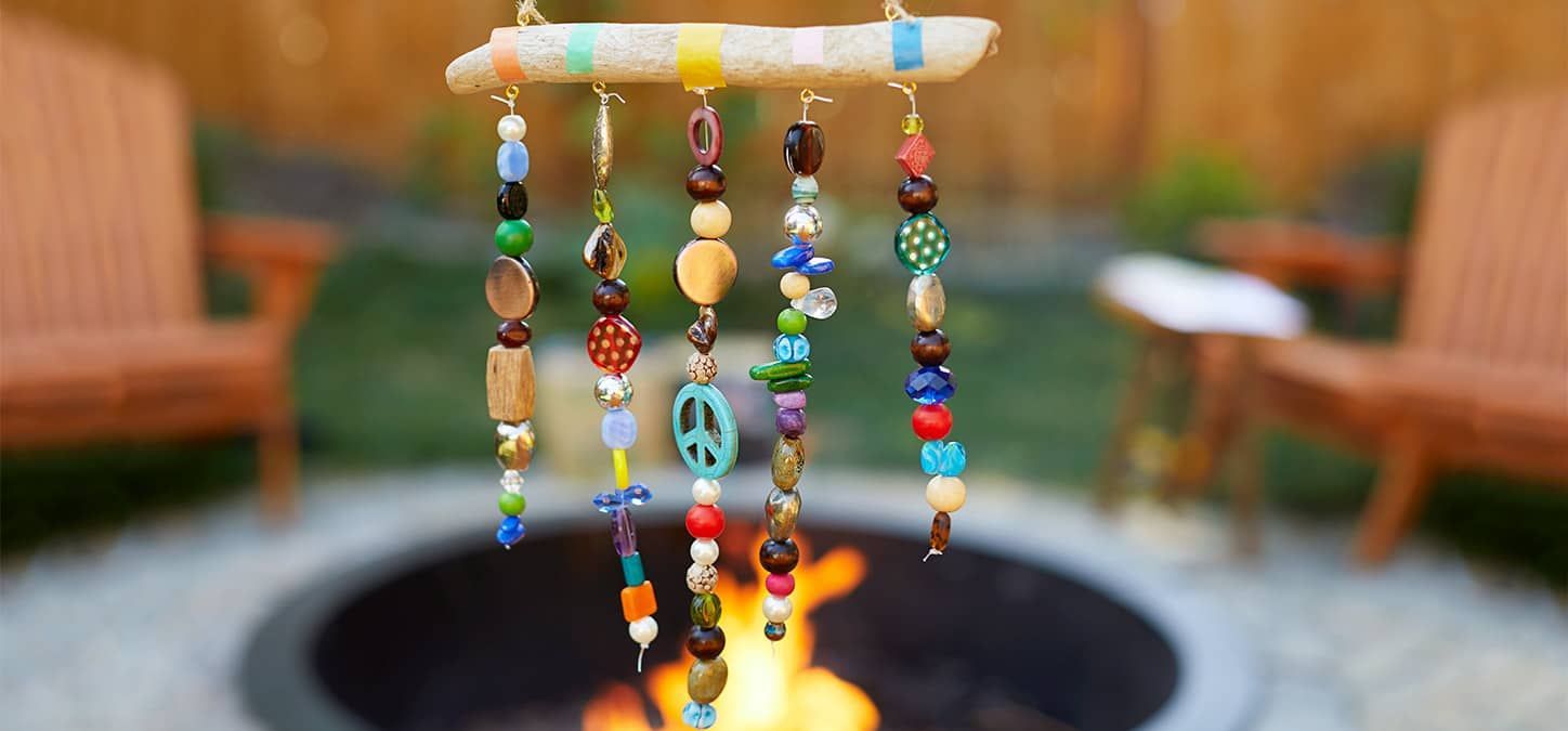 A wind chime made of beads is hanging near a fire pit.