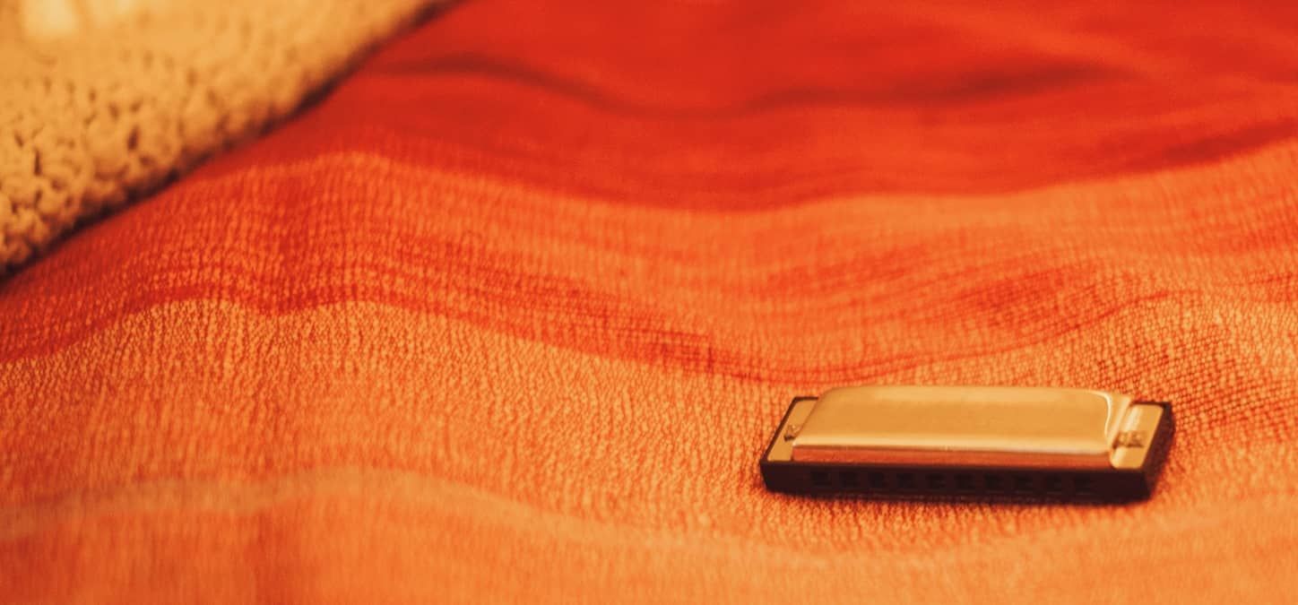 A harmonica is sitting on an orange blanket