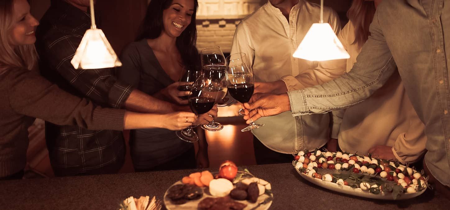 A group of people toasting with wine glasses in front of a glowing fireplace