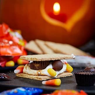 A s'more with candy corn and chocolate on top of a graham cracker.