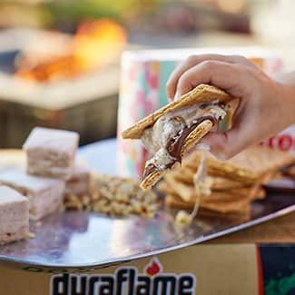 A person is holding a nutty about s'mores sandwich in their hand.