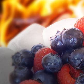 A pile of raspberries , blueberries and marshmallows with a fire in the background.