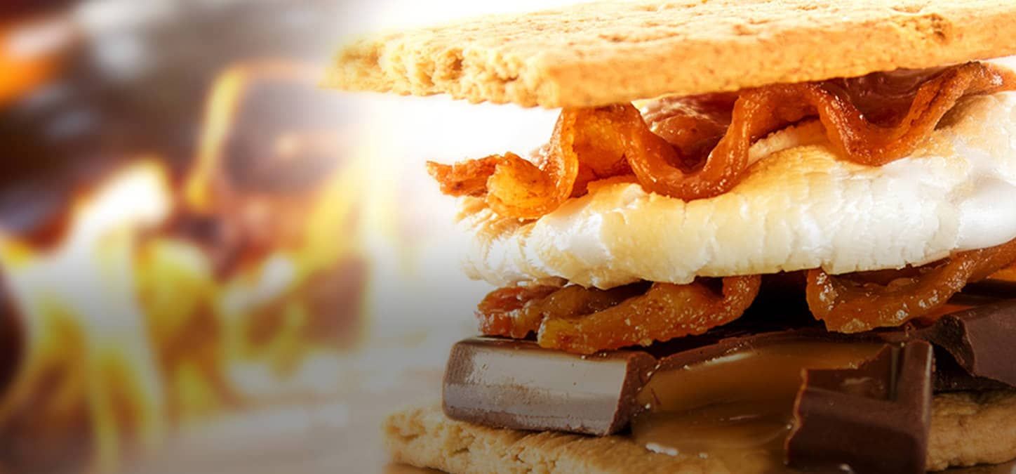 A s'more bacon sandwich with a fire in the background.