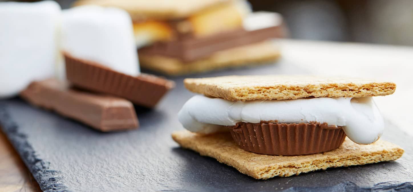 A s'mores with a peanut butter cup and roasted marshmallow in between two graham crackers