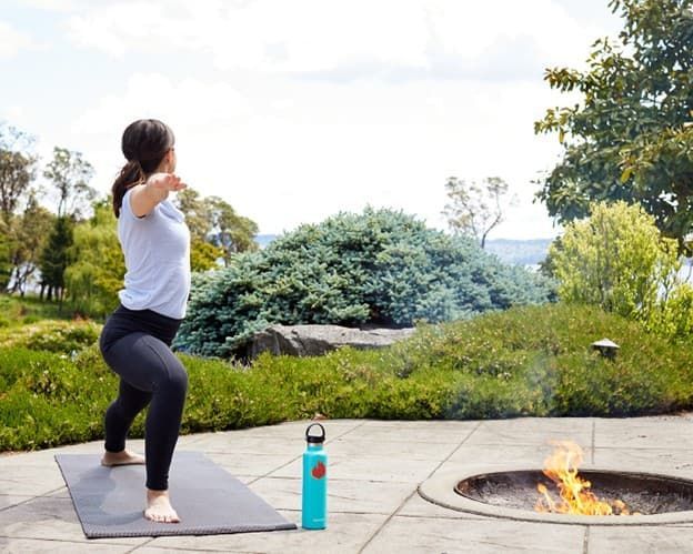 A woman is practicing yoga in front of a fire pit.
