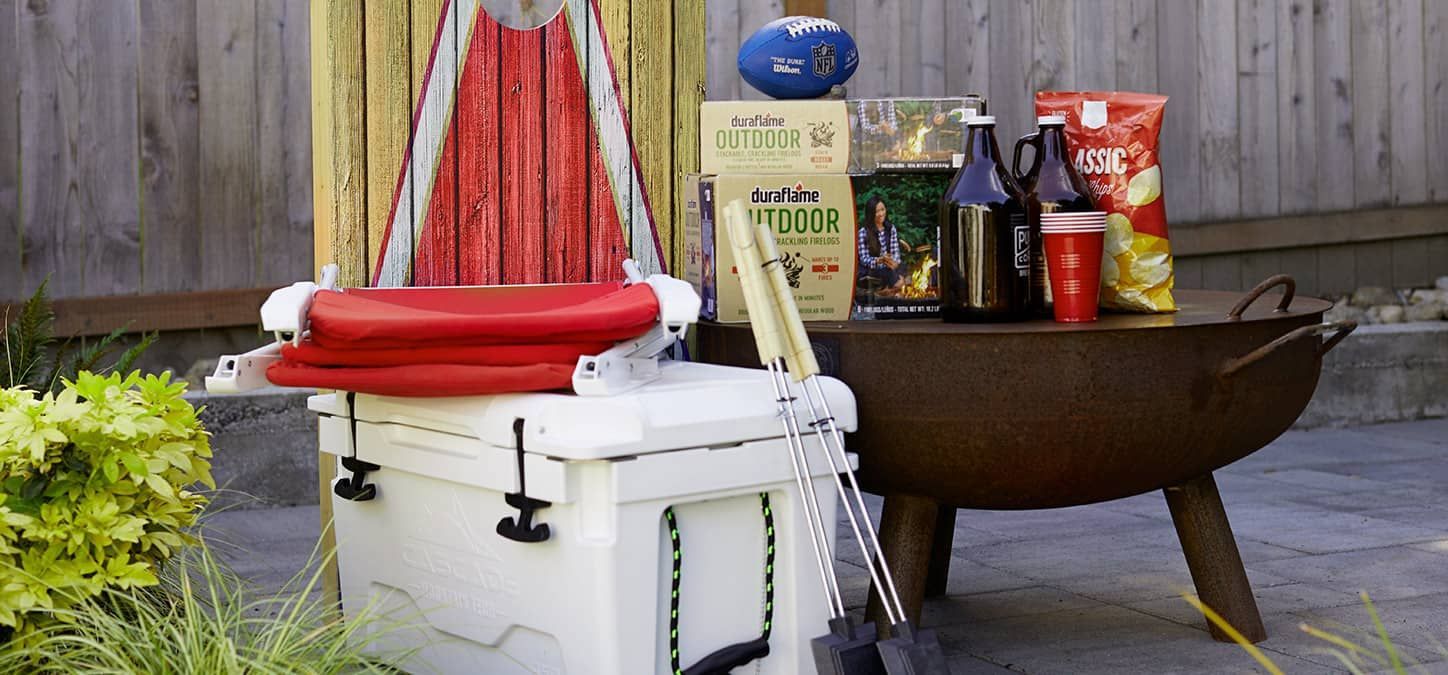 A white cooler is sitting on top of a table next to a fire pit.