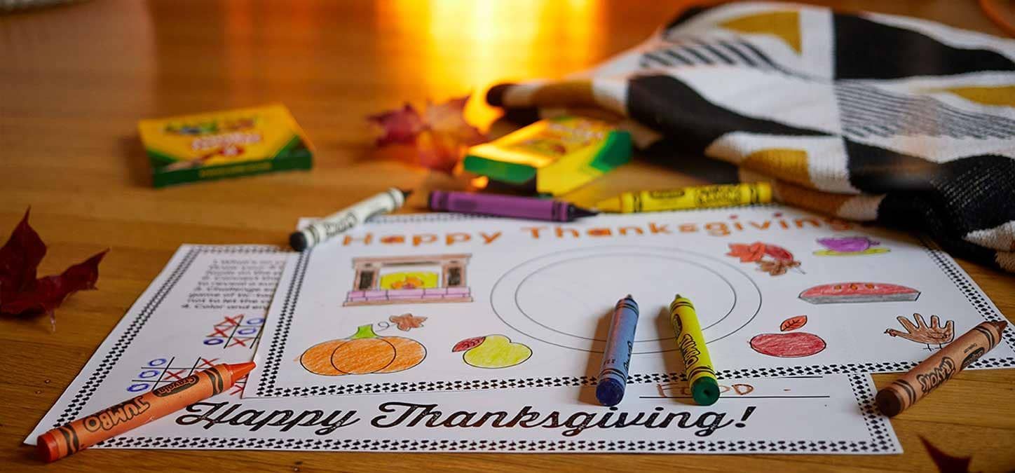 A happy thanksgiving coloring page with crayons and markers on a wooden table