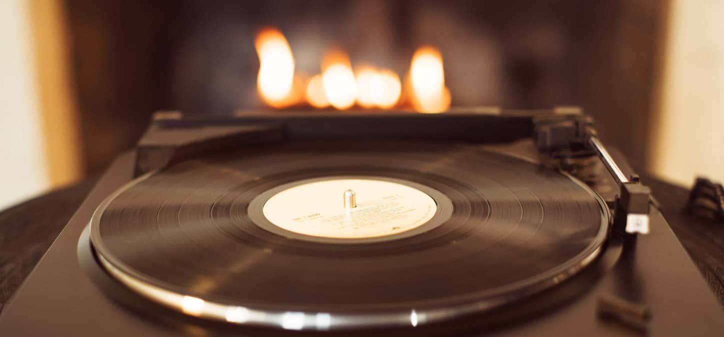 A record player is playing a record in front of a fireplace.