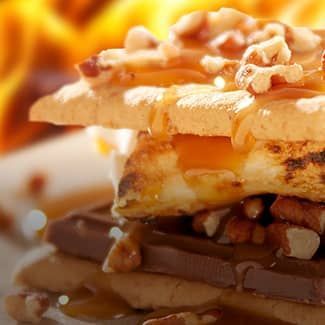 a turtle smores with marshmallows and chocolate with a fire in the background.