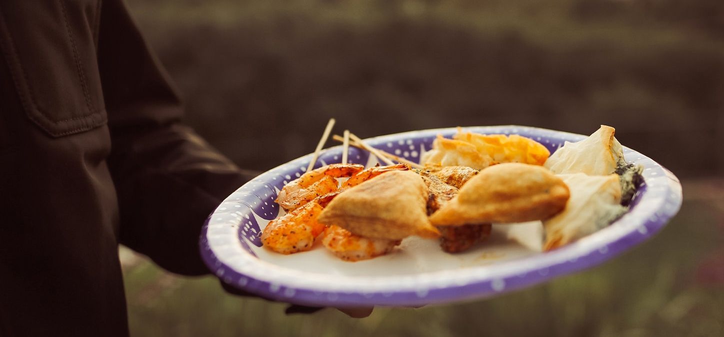 A person is holding a paper plate of chili garlic shrimp