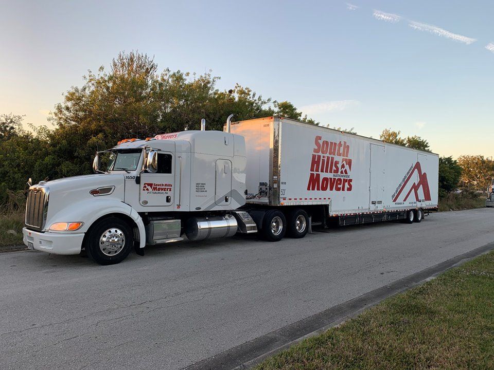 White semi-truck with trailer for South Hills Movers parked on road.