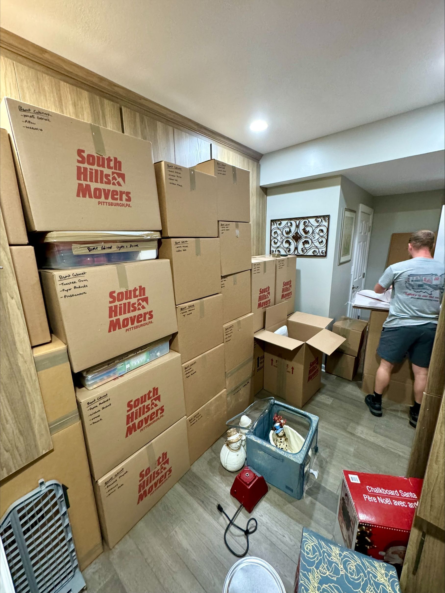 Boxes stacked in a room during a move. A person is carrying a box.