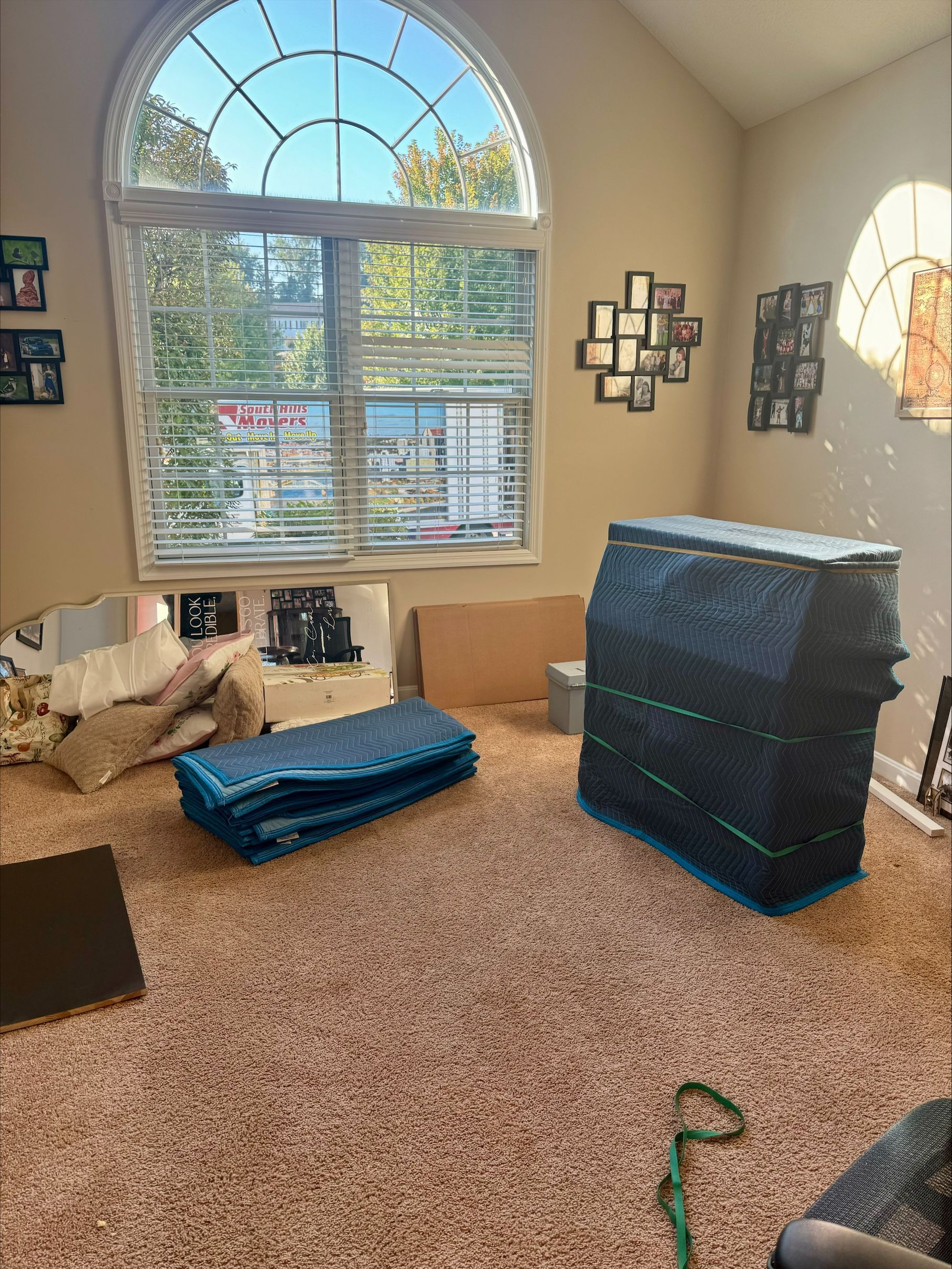 Room with large window, carpet, and stacked blue and black padding.