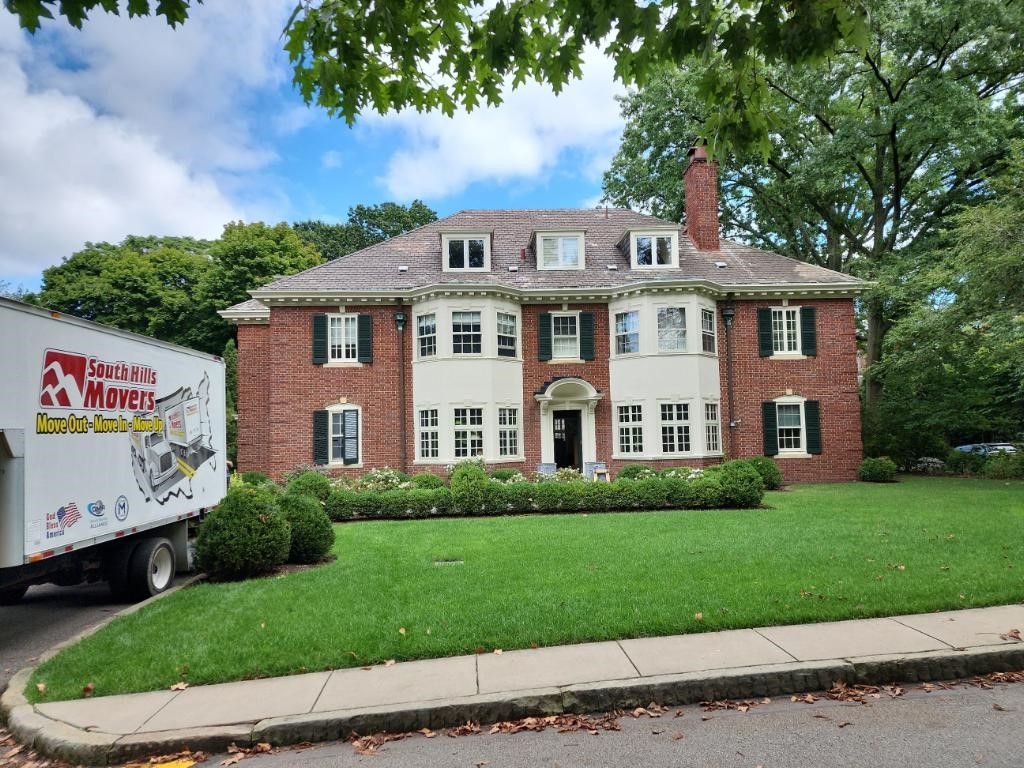 Moving truck parked in front of a brick house with a green lawn.