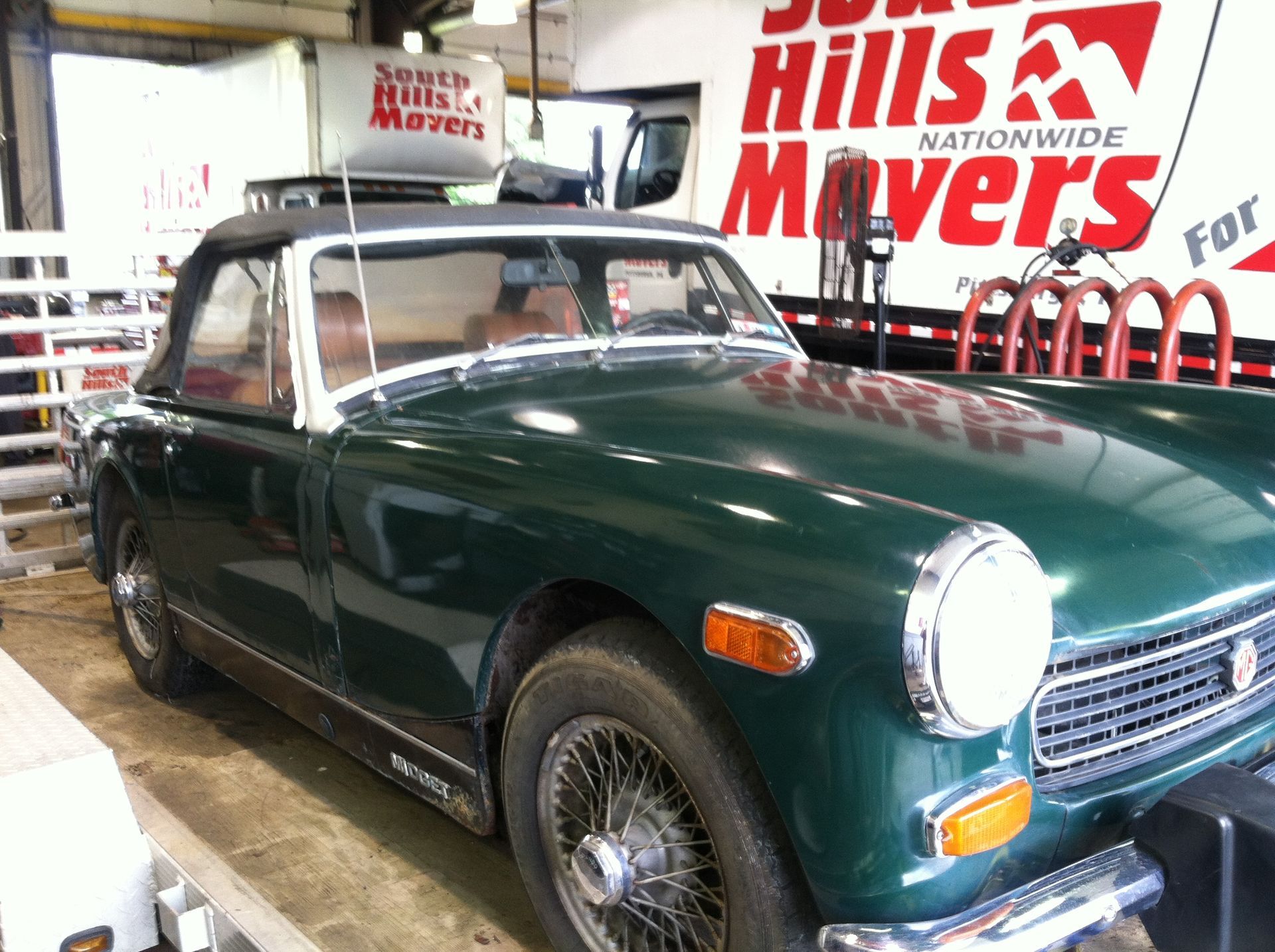 Green MG Midget convertible parked in front of a moving truck with the South Hills Movers logo.