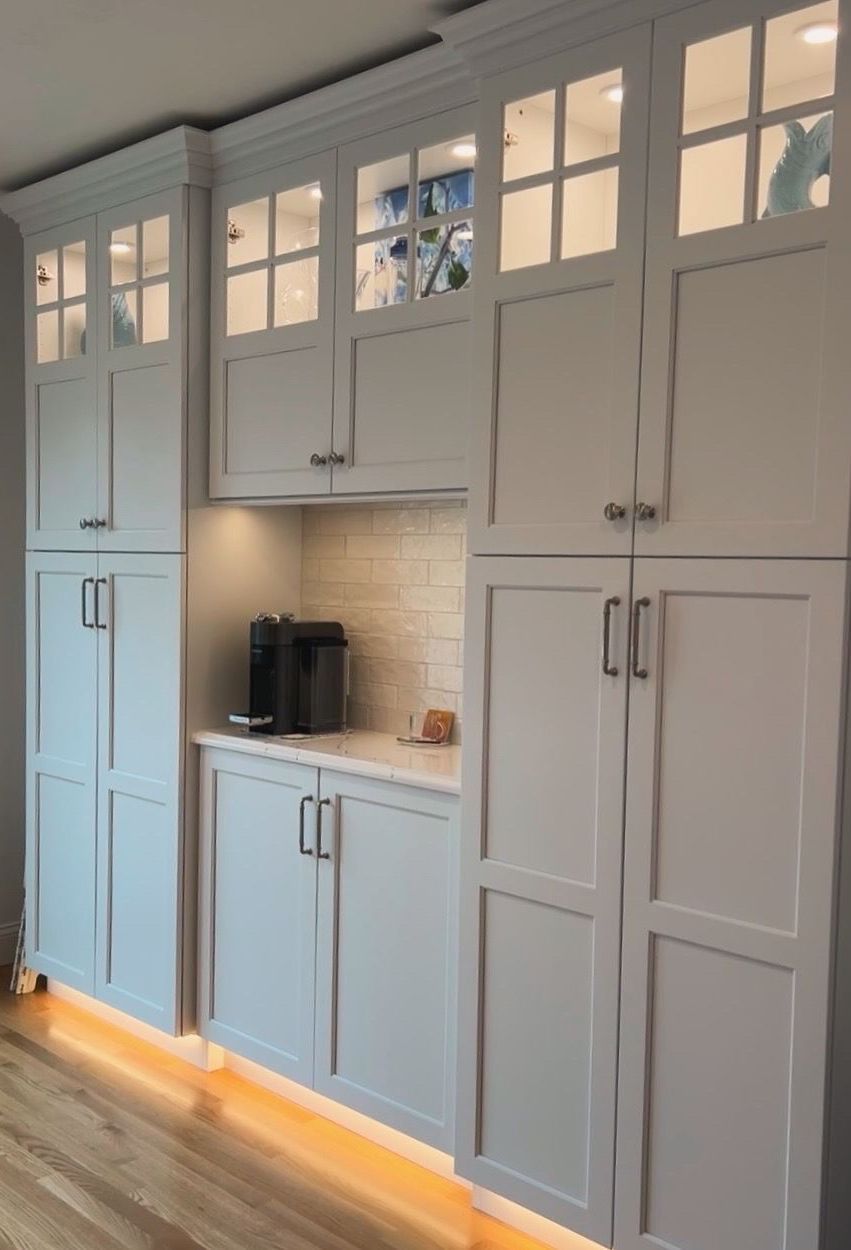 A kitchen with white cabinets and a wooden floor