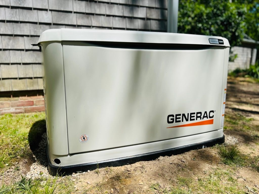 A generator is sitting in the grass in front of a house.