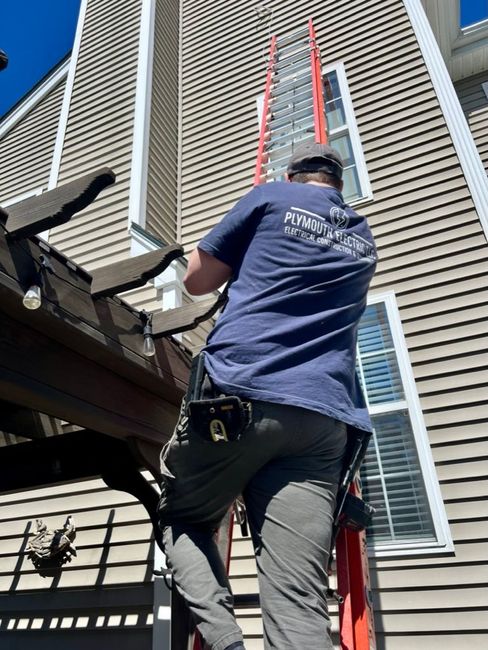 A man is standing on a ladder in front of a house.