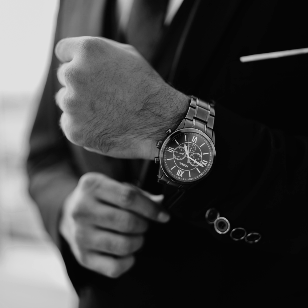 Silver wristwatch with black face, three subdials, and metal band.